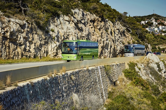 Two Mercedes-Benz Tourismo buses on a coastal road