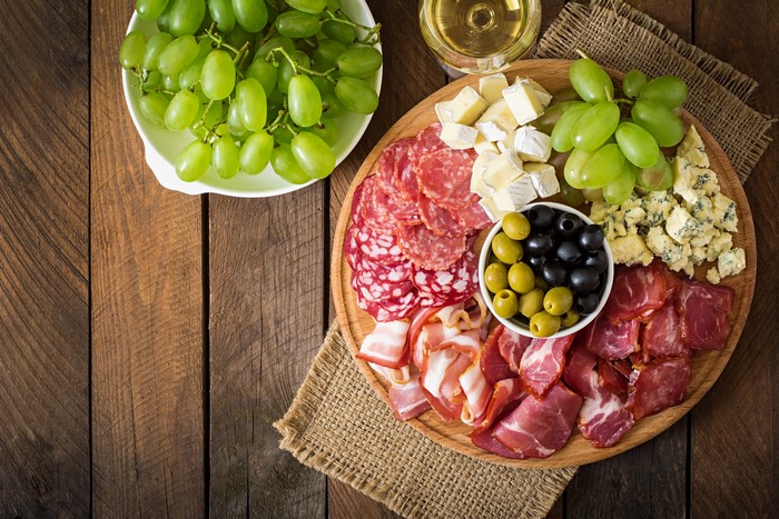 Charcuterie board with grapes, cheese, olives, and cured meats