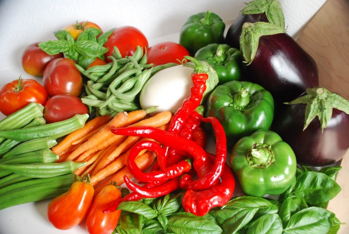 Assortment of fresh vegetables including tomatoes, bell peppers, carrots, and eggplants