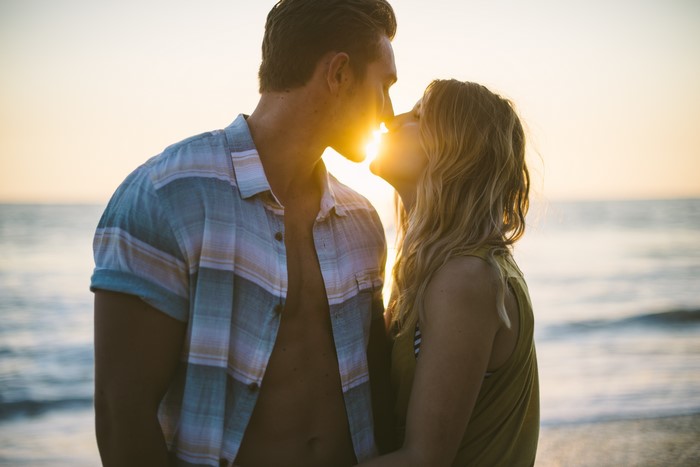 Couple kissing on the beach at sunset