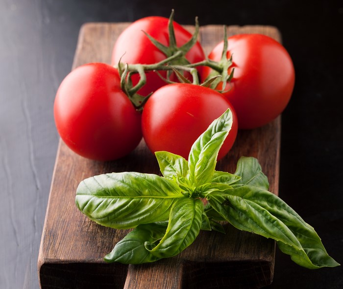 Tomatoes and basil on a wooden cutting board