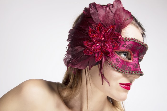 Woman wearing a burgundy masquerade mask with feathers