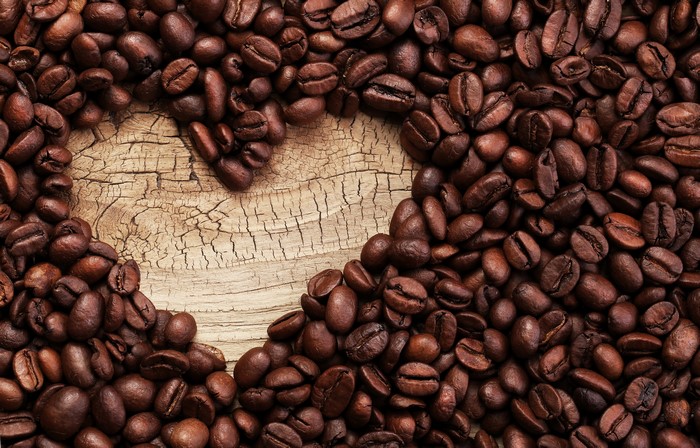 Heart shape made of coffee beans on wood
