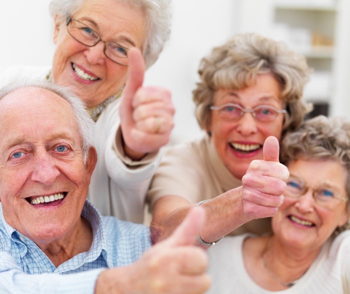 Four elderly people giving thumbs up