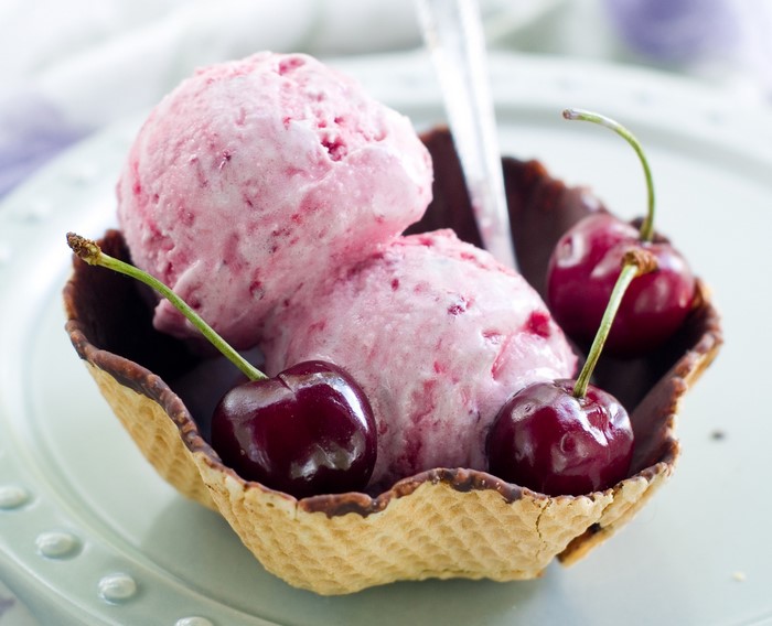 Cherry ice cream scoops in a waffle bowl with cherries
