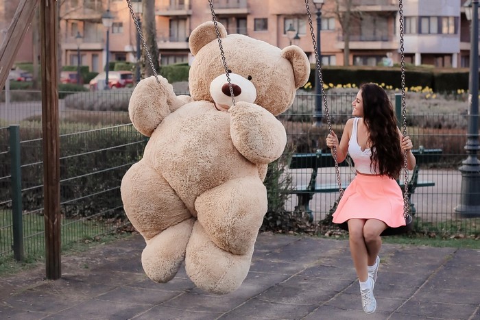 Giant teddy bear and girl on a swing