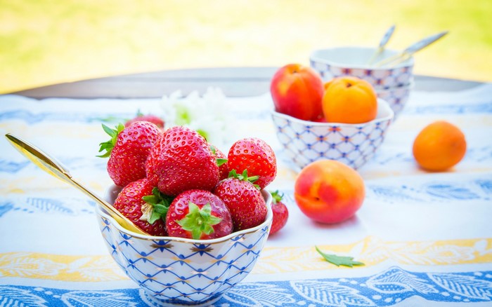 Strawberries and peaches in bowls on a table