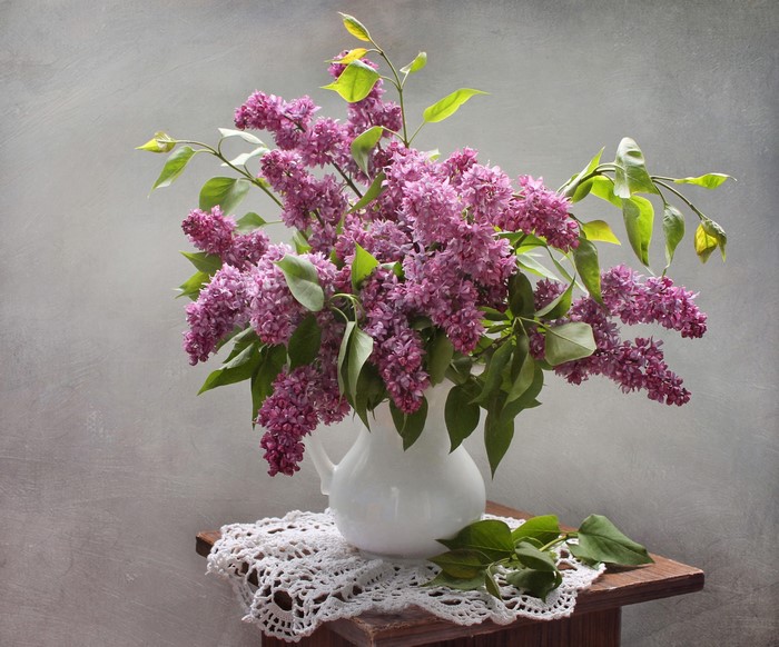 Bouquet of purple lilacs in a white vase on a table