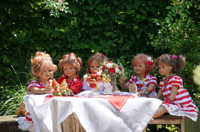Five dolls having a tea party with strawberries