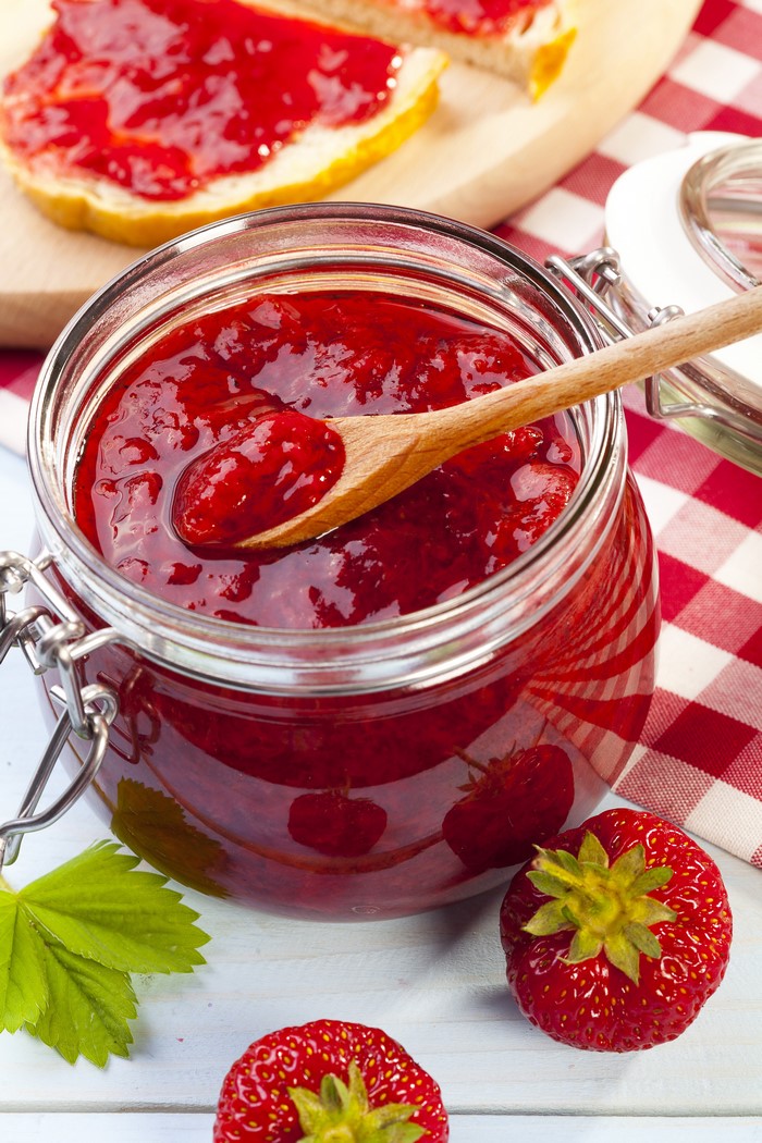Fresh Strawberry Jam in Glass Jar with Wooden Spoon