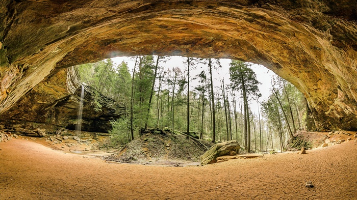 Cave opening with waterfall and forest