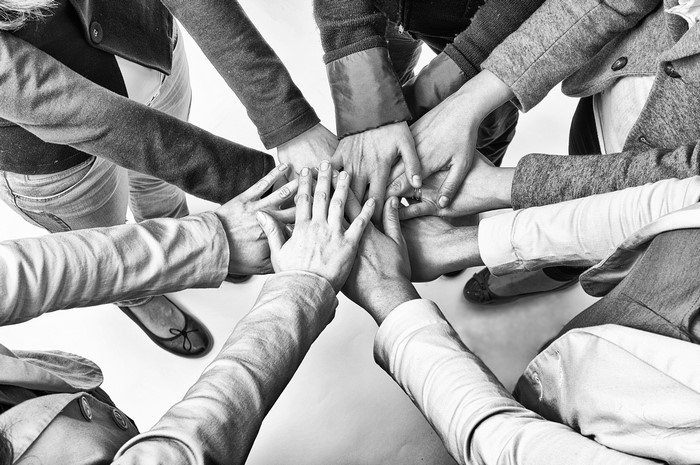 Many hands stacked together in black and white