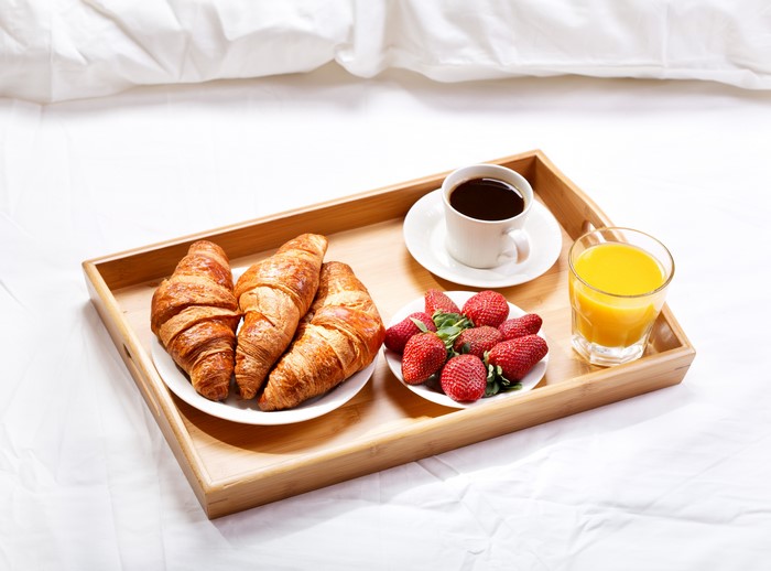 Breakfast tray with croissants, strawberries, coffee, and orange juice
