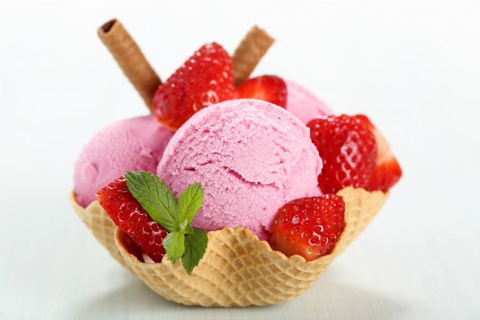 Strawberry ice cream in a waffle bowl with strawberries and wafer sticks