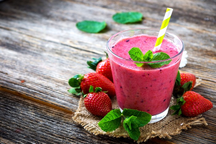 Strawberry smoothie with mint and strawberries on wood