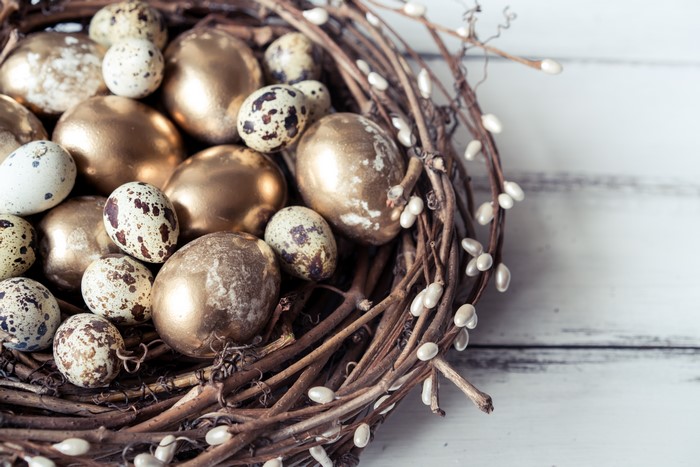 Golden and speckled eggs in a nest
