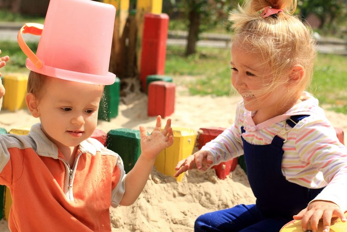 Children playing in a sandbox with a bucket