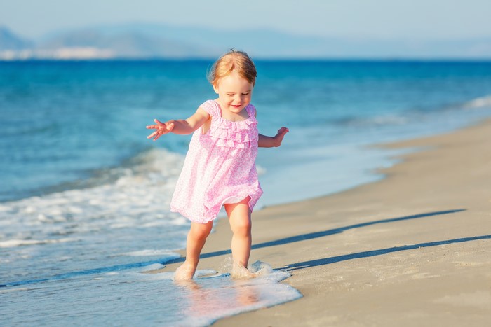 Little girl in pink dress on the beach