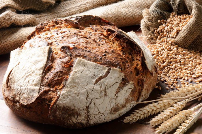 Rustic loaf of bread with wheat grains and stalks