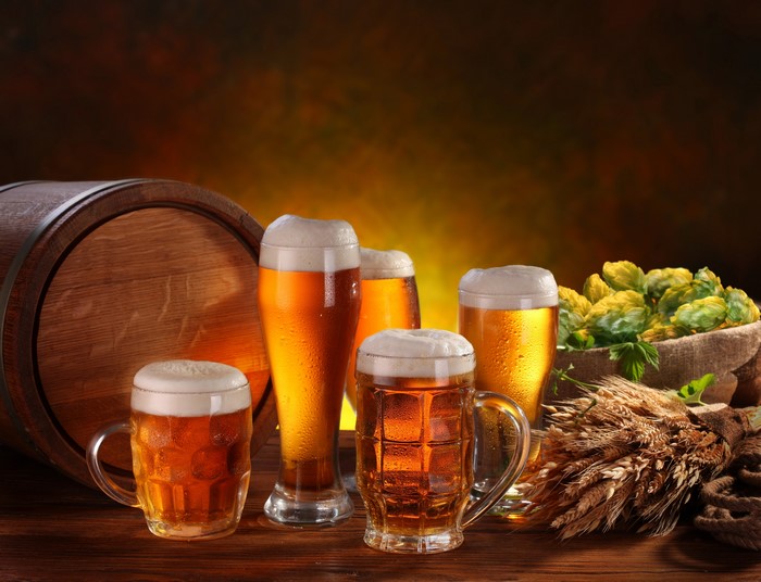 Beer in mugs and glasses with barrel and hops
