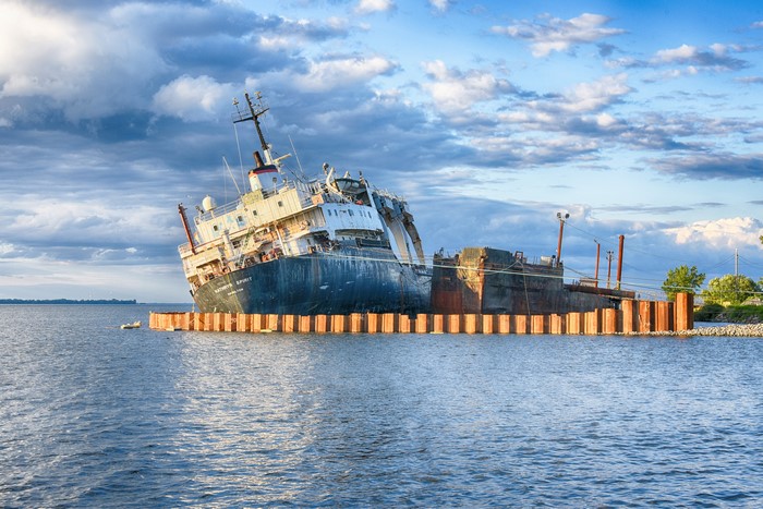 Shipwrecked vessel in water with clouds