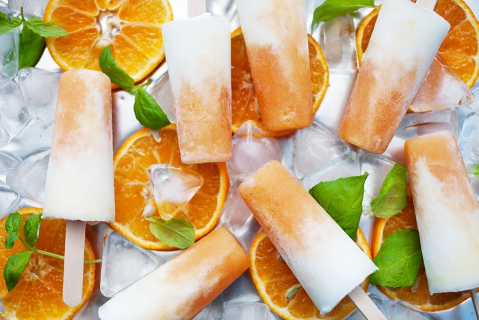 Orange and white popsicles with oranges and ice