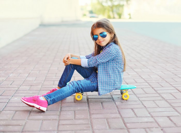 Girl in sunglasses sitting on a skateboard