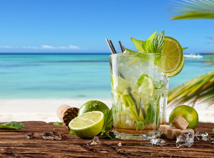 Mojito cocktail with limes and mint on a beach