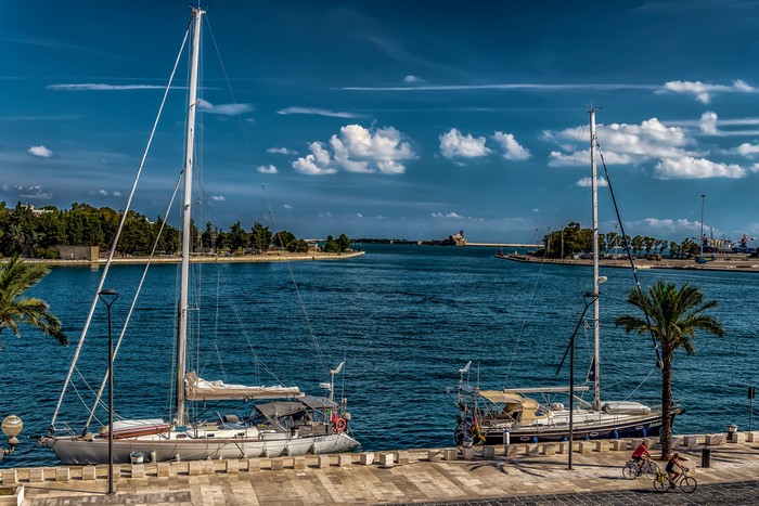 Sailboats docked in Brindisi, Italy harbor with cyclists