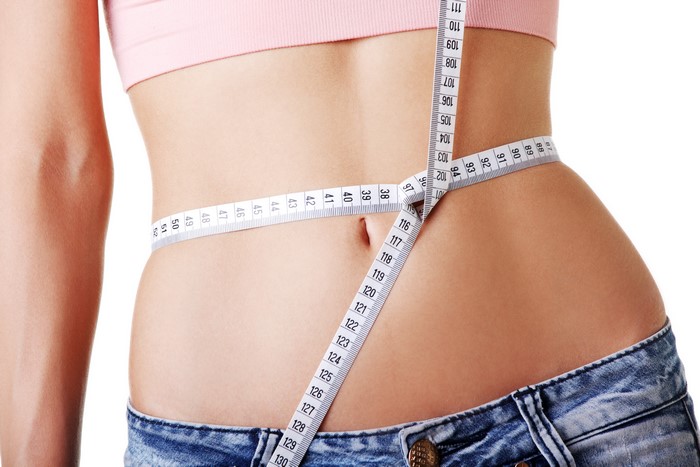 Woman measuring waist with tape measure