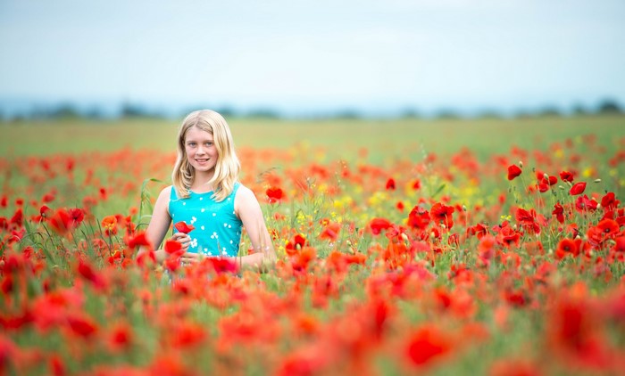 Blonde girl in a field of poppies