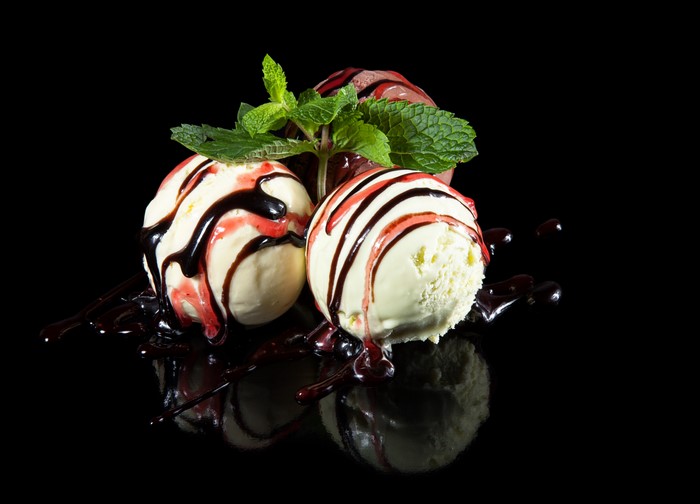 Ice cream scoops with chocolate and strawberry syrup and mint leaves
