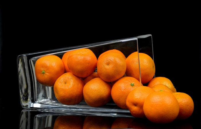 Tangerines in a glass vase on a black background