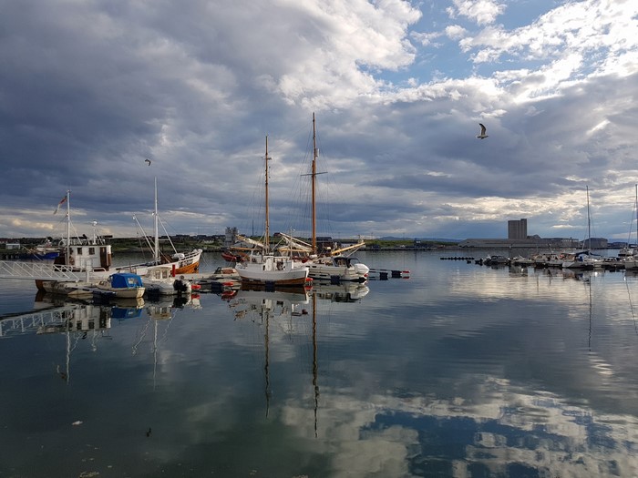 Boats docked in a harbor under a cloudy sky