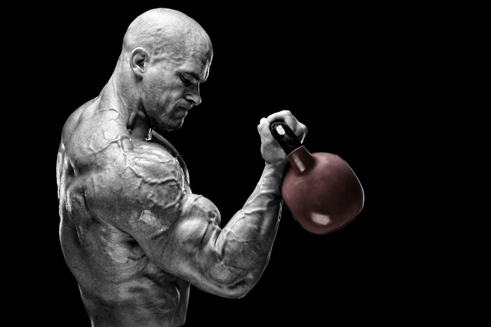 Bodybuilder performing kettlebell bicep curl