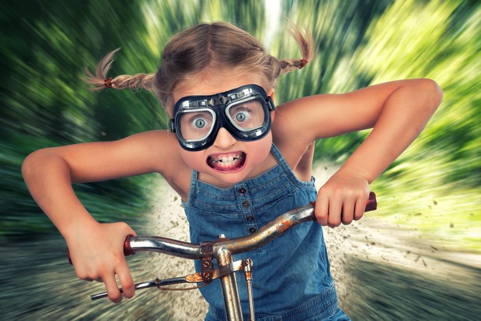 Girl in goggles riding a bicycle with motion blur