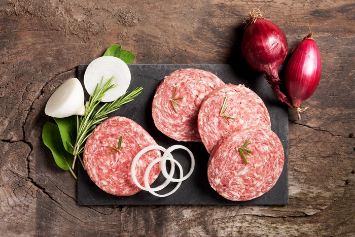 Sausage slices with onion and rosemary on a wooden board