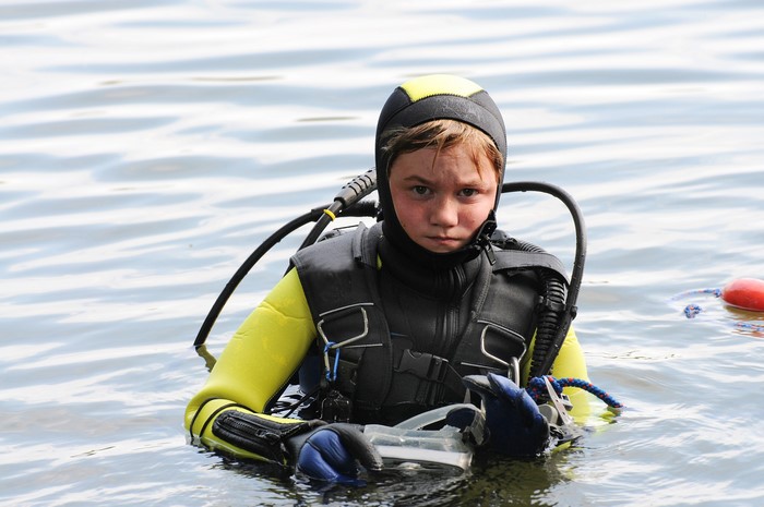 Young diver in a wetsuit and scuba gear in water