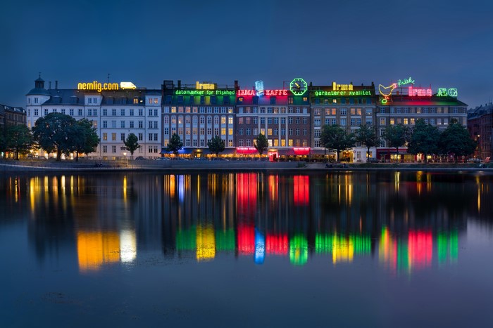 Copenhagen buildings with neon signs reflected in water at dusk