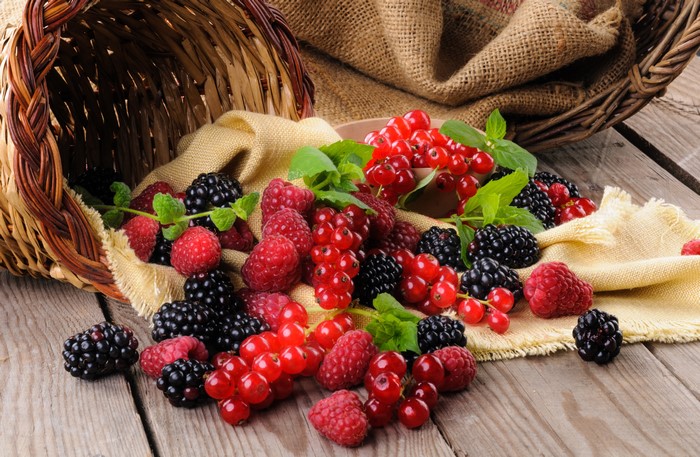 Berries spilling from a wicker basket onto wooden planks