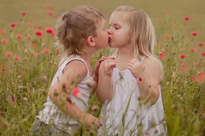 Young Boy and Girl Sharing a Kiss in Poppy Field
