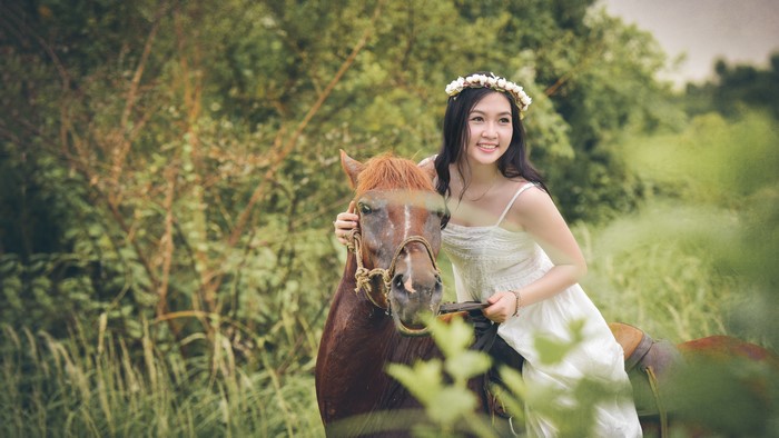 Brunette girl with flower wreath on horse