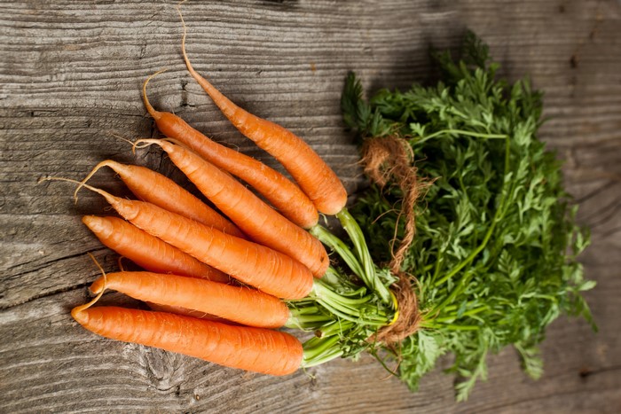 Carrots with green tops on wood planks