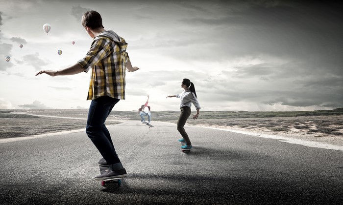 People skateboarding on a road with hot air balloons