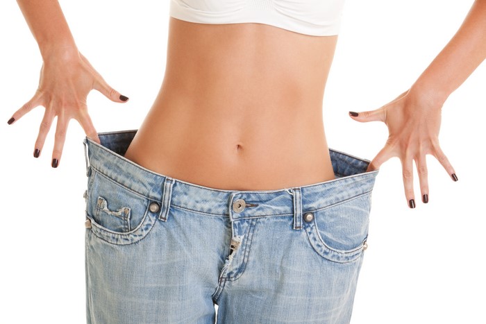 Woman in oversized jeans showing weight loss