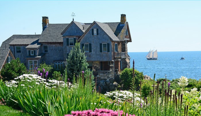 House on a cliff overlooking the ocean with a sailboat