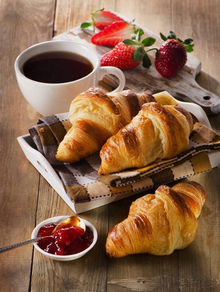 Croissants with jam and strawberries and a cup of tea