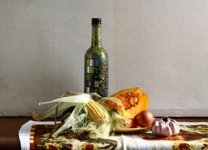 Still-life with bottle, corn, pumpkin, onion, and garlic