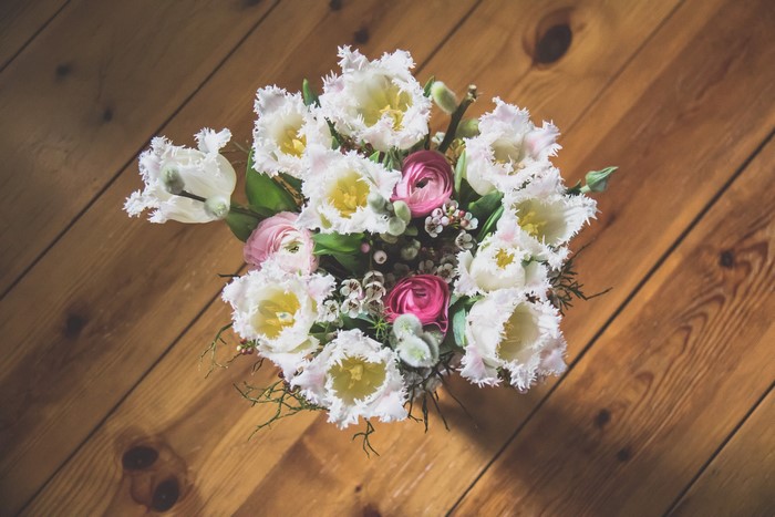 Bouquet of white tulips and pink ranunculus on wood