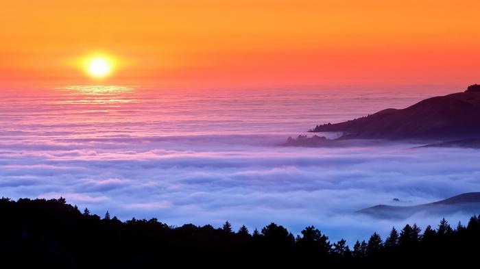 Sunset over a sea of clouds and coastal hills